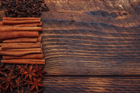 Cinnamon sticks, anise stars and cloves close-up with blank space for text on brown wooden background, concept of cooking spicy food, baking and drinks, Christmas, ingredients and seasoningsの写真素材