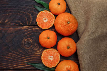 Orange citrus tangerines with green leaves and linen napkin on brown wooden background with empty space for text, copy space, flat lay, concept of seasonal fruits and vitamins, Christmas recipeの写真素材
