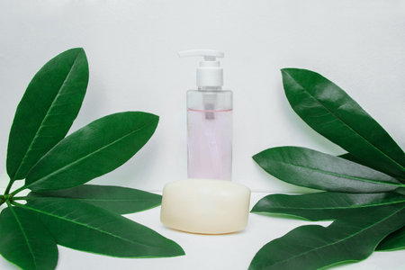 Plastic cosmetic bottle dispenser with gel and bar of soap on white background close-up with green leaves, with empty space for text, copy space, product advertising template concept and labelsの写真素材