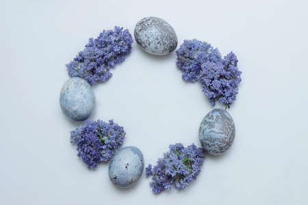 Round frame with wreath of Easter eggs painted in blue purple lilac and muscari flowers on white background with empty space for text, copy space, closeup, greeting card design concept, spring holidayの写真素材