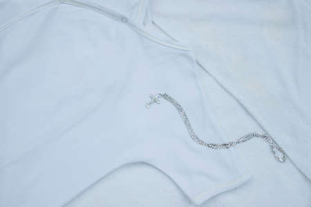 Out of focus with film effect and noise, white children's clothes for christening party, shirt and towel with silver chain and cross, concept of church Christian sacraments and traditions, religionの写真素材