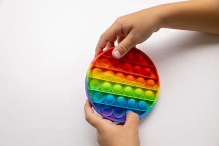 popping fidget toy is a popular new fashionable toy for children and people with stress on a white background. A Toy With A Rainbow Bubble For Children. A toy in the hands of a child. copispaceの写真素材