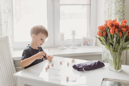 a lotto game. A boy child is playing a lotto game at a white table on a light background.の写真素材