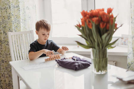 a lotto game. A boy child is playing a lotto game at a white table on a light background.の写真素材