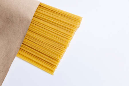 Italian raw spaghetti on craft paper. Close-up. on a white background. Italian cuisine or culinary concept.の写真素材