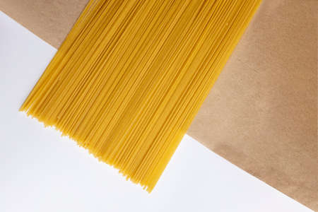 Italian raw spaghetti on craft paper. Close-up. on a white background. Italian cuisine or culinary concept.の写真素材