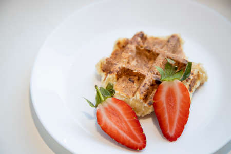Viennese Belgian waffle with strawberries on a white plate and a white backgroundの写真素材
