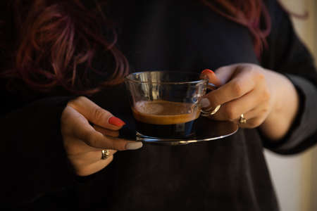 in the girl's hands is a transparent cup of coffeeの写真素材