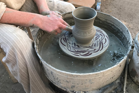 Close up of a potter master working behind a pottery wheel. Pottery, modeling of blue clay. Freshly...