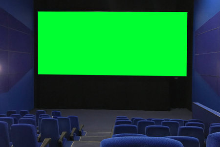 View of the empty cinema hall and a large green screen from the top rows. Cinema with rows of blue...