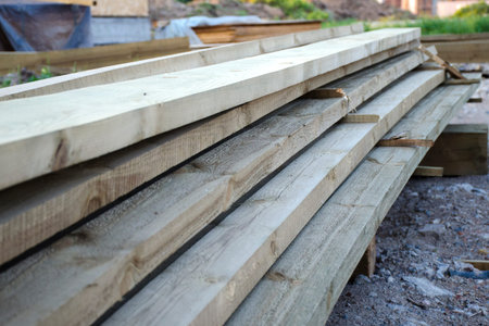 Close-up of a stack of long wooden boards. The concept of building wooden country houses