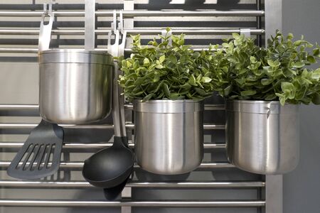 Kitchen railing with utensils and metal pots with flowers in gray colorsの写真素材