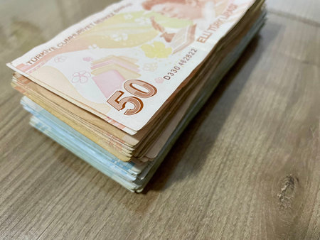 Close-up of many turkish banknotes of different denominations lying in a stack on a wooden table....