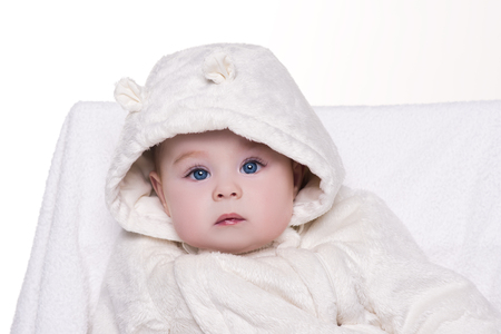 portrait of a cute baby in white hood bear. baby with big blue eyes sitting on a chair and looking into the cameraの写真素材