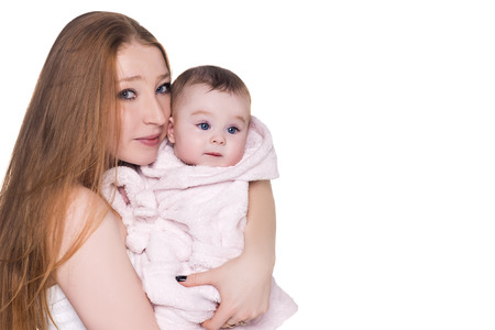 loving mother with her cute baby isolated on white. mom holding child in pink bathrobe hood with blue eyes, after shower. happy family conceptの写真素材