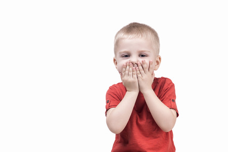 cute child boy surprised by something and closed mouth hands. teenager on white backgroundの写真素材