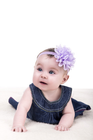 portrait of cute little baby girl with bow flower on her head. kid looks away with admiration. child girl with big blue eyes. happy family conceptの写真素材