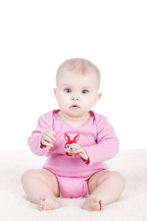 cute little baby girl in pink bodysuit sitting on a blanket and looking at the camera. child girl with big blue eyes. happy f1amily conceptの写真素材