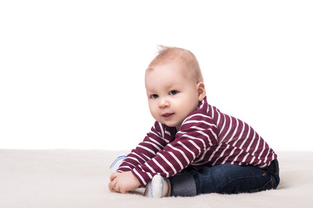 cute baby boy with big hazel eyes sitting on a blanket and smiling. child on a white background, isolated. happy family conceptの写真素材