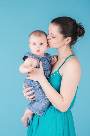 loving young mother kissing her cute baby. surprised child with big blue eyes looks at the cameraの写真素材
