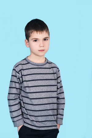 portrait of child boy with hands in pockets isolated on blue backgroundの写真素材
