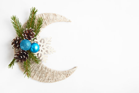 Fir tree branch, blue balls and pine cones on white crescent and snowflake. Top view with copy...