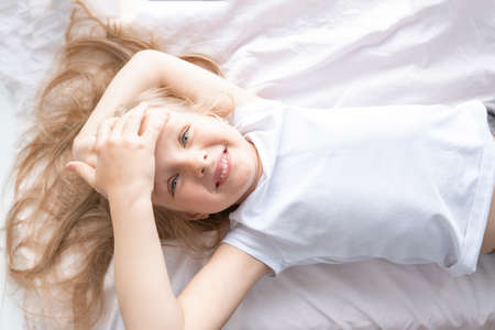 happy little girl is lying at home and smilingの写真素材