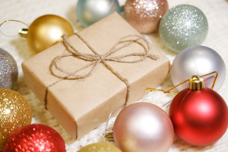 Christmas gift box in craft paper with close-up, colorful Christmas ballsの写真素材