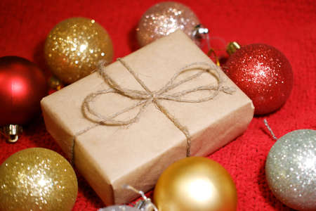 Christmas gift box in craft paper with close-up, colorful Christmas ballsの写真素材