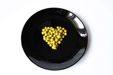 heart-shaped green polka dots on a black saucer with a white background close-upの写真素材