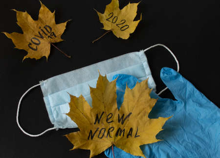 Autumn composition of maple leaves on a black background with a mask and gloves. The view from the top. the Covid-19 concept. new realityの写真素材