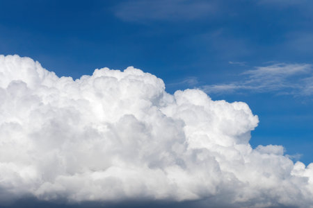 Big white fluffy cumulus cloud against blue sky background.