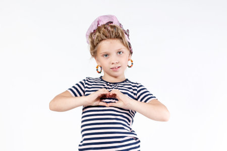 Cute little blond girl smiling and showing heart symbol isolated against white backgroundの写真素材