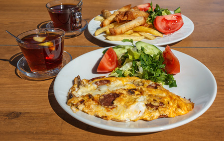 Traditional Turkish breakfast outdoor served. plate with greens and omelet with  sausage and mushroomsの写真素材