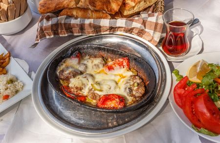 Traditional Turkish food. Roast meatballs baked in a cast-iron shape with garnish  outdoor served.の写真素材