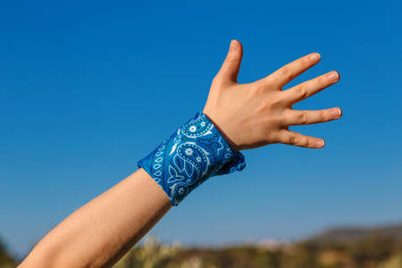 female hand with a blue bandana with palm hand on nature background (bunch of fives)の写真素材