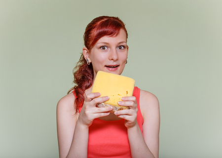 young beautiful girl with a piece of cheddar cheeseの写真素材