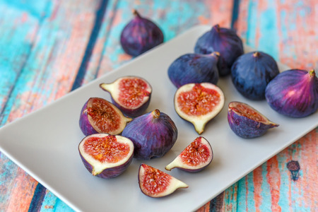 Purple figs on bright plate on a surface that mimics an old treeの写真素材
