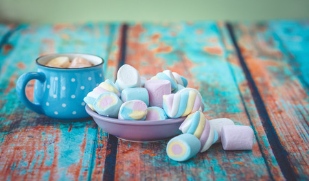 Different kinds of marshmallow on wooden table and cup of coffee. Photo toned with vignette.の写真素材