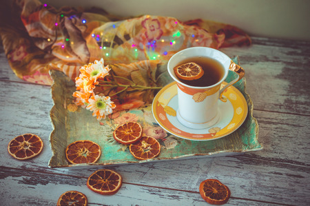 cup of tea with dried orange slices and autumn flowers on a tray and wooden table.
photo toned and with vignette.の写真素材