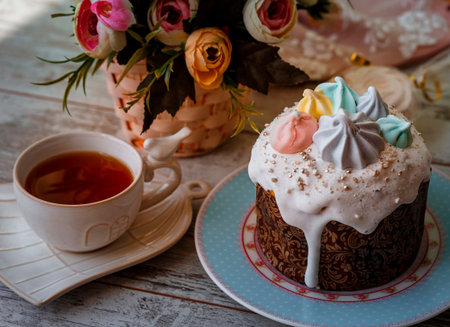 Easter cake decorated with marshmallow and icing, tea, marshmallow and napkin on a wooden table
