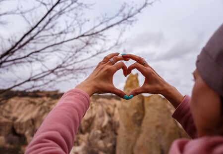CAPPADOCIA, TURKEY â APRIL 16, 2019: Female hands in the shape of heart symbol in Cappadocia, Goreme Open-Air Museum. Focus on heart shaped fingersのeditorial素材