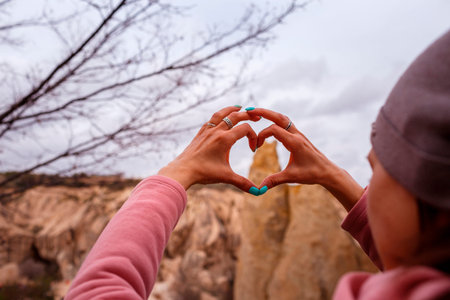 CAPPADOCIA, TURKEY â APRIL 16, 2019: Female hands in the shape of heart symbol in Cappadocia, Goreme Open-Air Museum. Focus on heart shaped fingersのeditorial素材