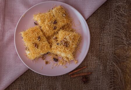 Turkish dessert muhallebi kadaif with nuts on a plate and a napkin on canvasの写真素材