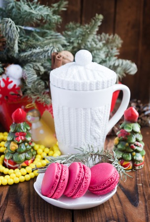 Pink macaroons with christmas decorations and white cup on wooden backgroundの写真素材
