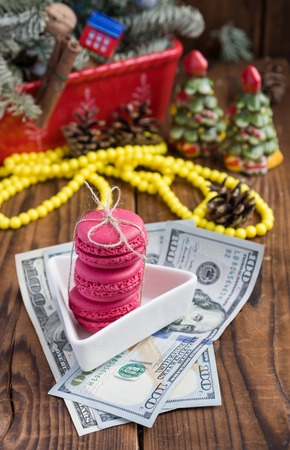 Pink macaroons and twenty dollars with christmas decorations on woooden backgroundの写真素材