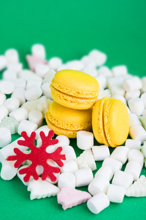 Yellow macaroons, marshmallow and red flake on greenの写真素材