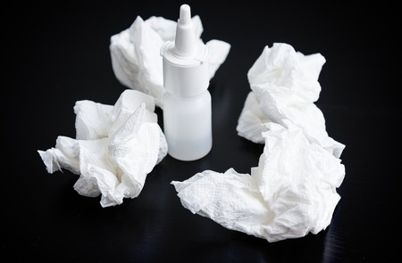 Nasal spray, nasal drops,nd crumpled handkerchief on tableの写真素材