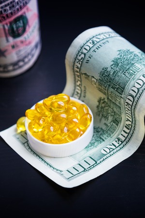 Capsules of fish oil and dollars on black backgroundの写真素材