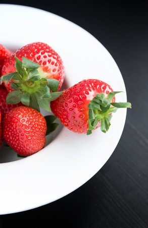 Fresh strawberries on plate on black backgroundの写真素材